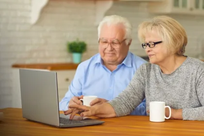 Senior couple researching financial assistance programs on a laptop